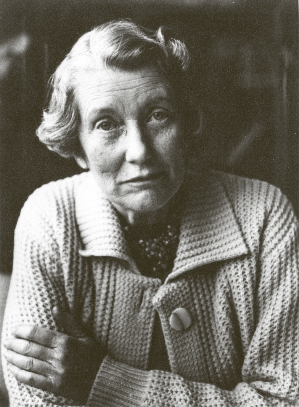 Portret van Lilian Posthumus-van der Goot, begin jaren zestig, gekleed in lichtgekleurd vest met grote parelketting. Collectie IAV, Archief Posthumus-van der Goot, inv.nr. 2271.